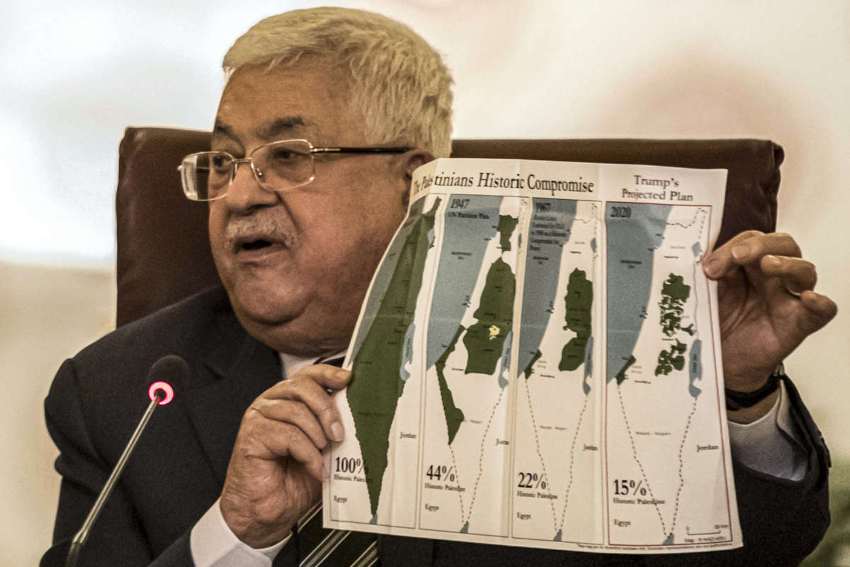Palestinian president Mahmoud Abbas holds a placard showing a series of maps of Palestine at the Arab League headquarters in the Egyptian capital Cairo on February 1, 2020.
