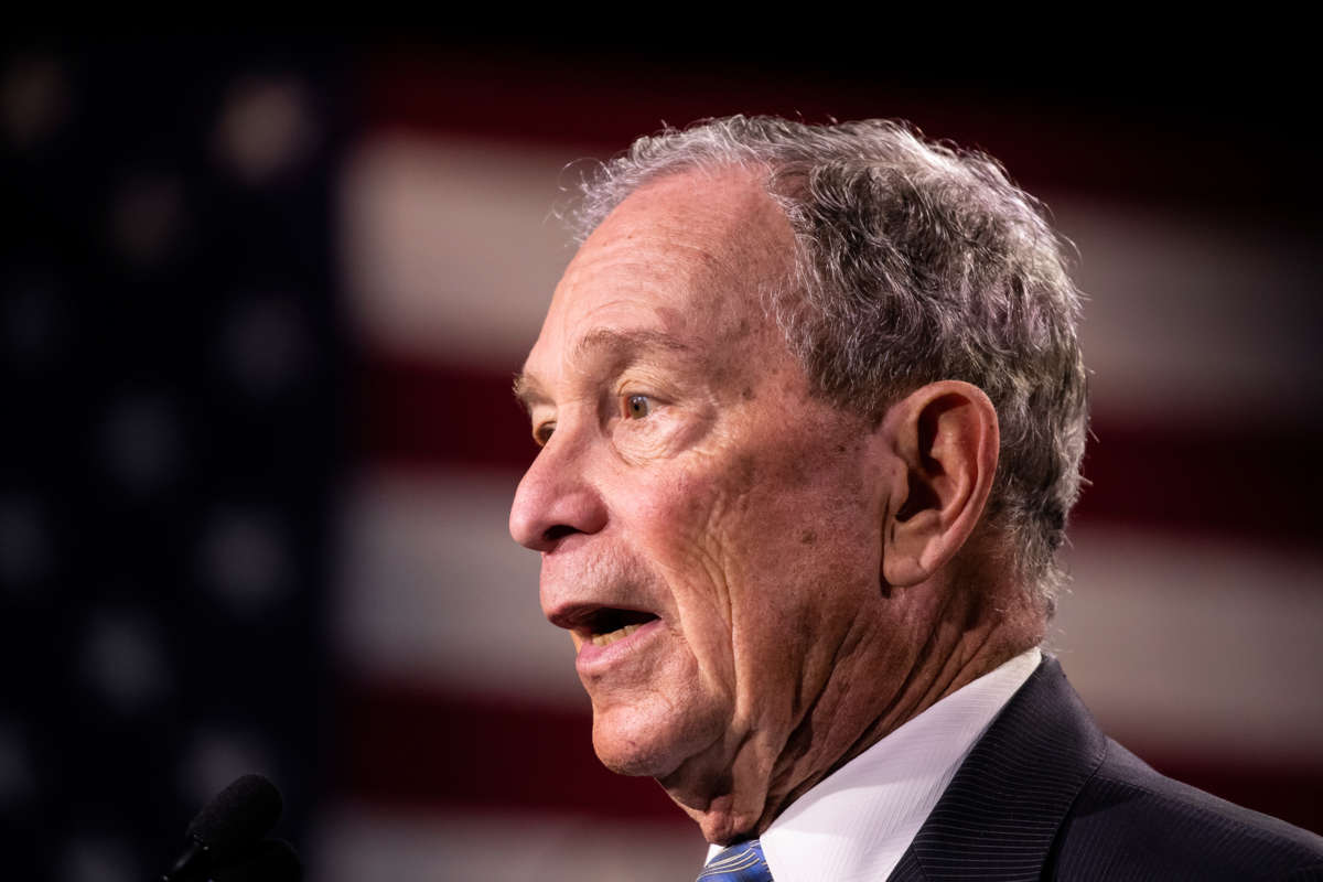 Mike Bloomberg, whose countenance looks remarkably similar to George W. Bush's in this photo, speaks in front of a U.S. Flag