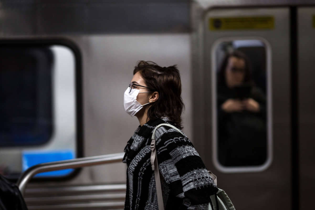 A woman wearing a face mask walks by a public train