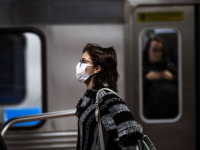 A woman wearing a face mask walks by a public train