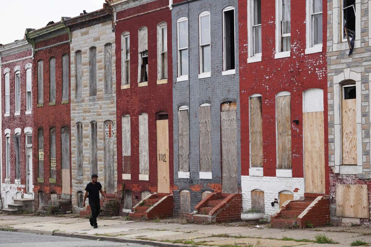 A pedestrian passes by a row of boarded up houses in east Baltimore, Maryland, on August 8, 2017.