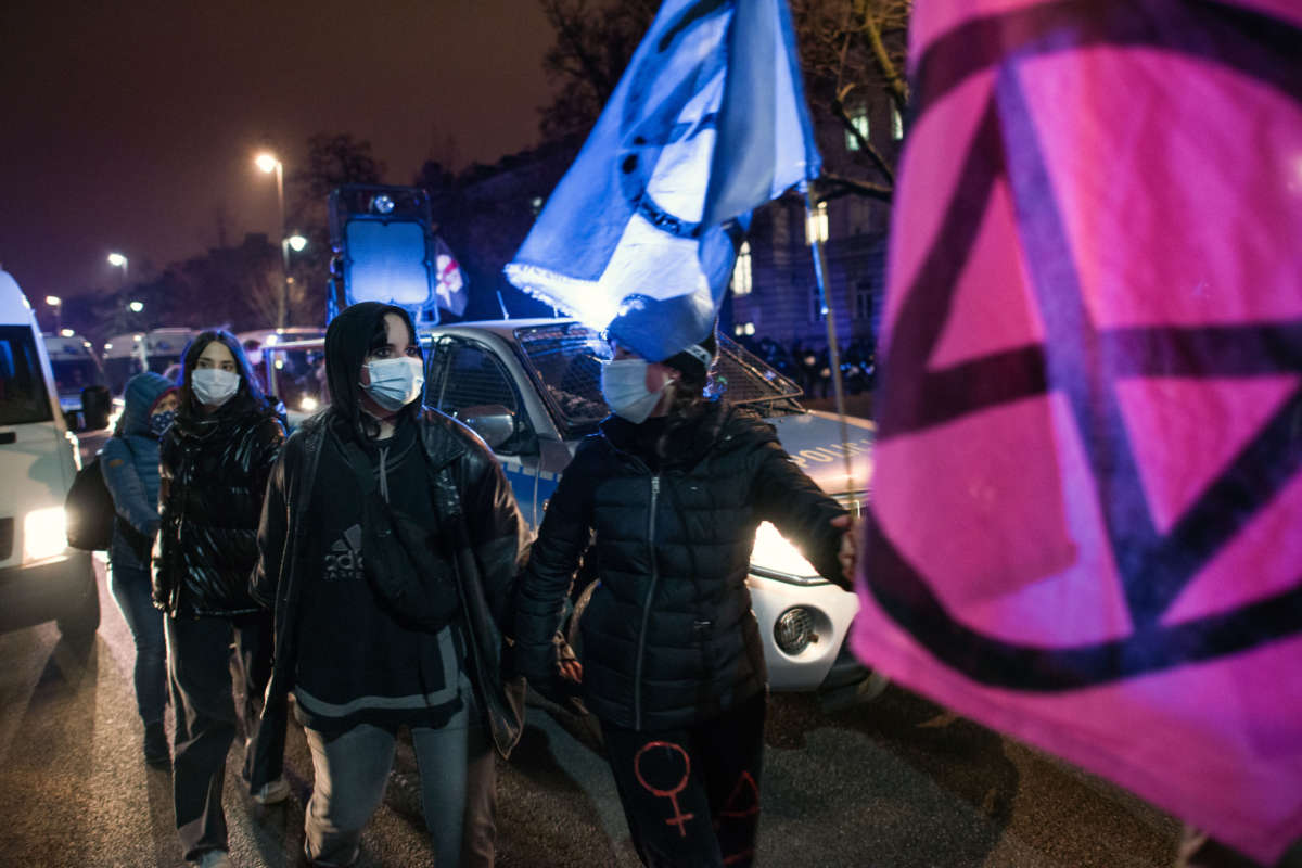 Masked youths carring Extinction Rebellion flags march in the night