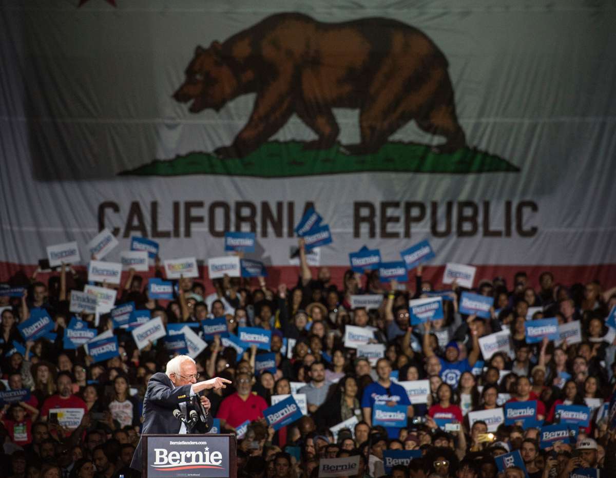 Bernie Sanders stands in front of California's state flag during a campaign event