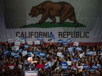 Bernie Sanders stands in front of California's state flag during a campaign event