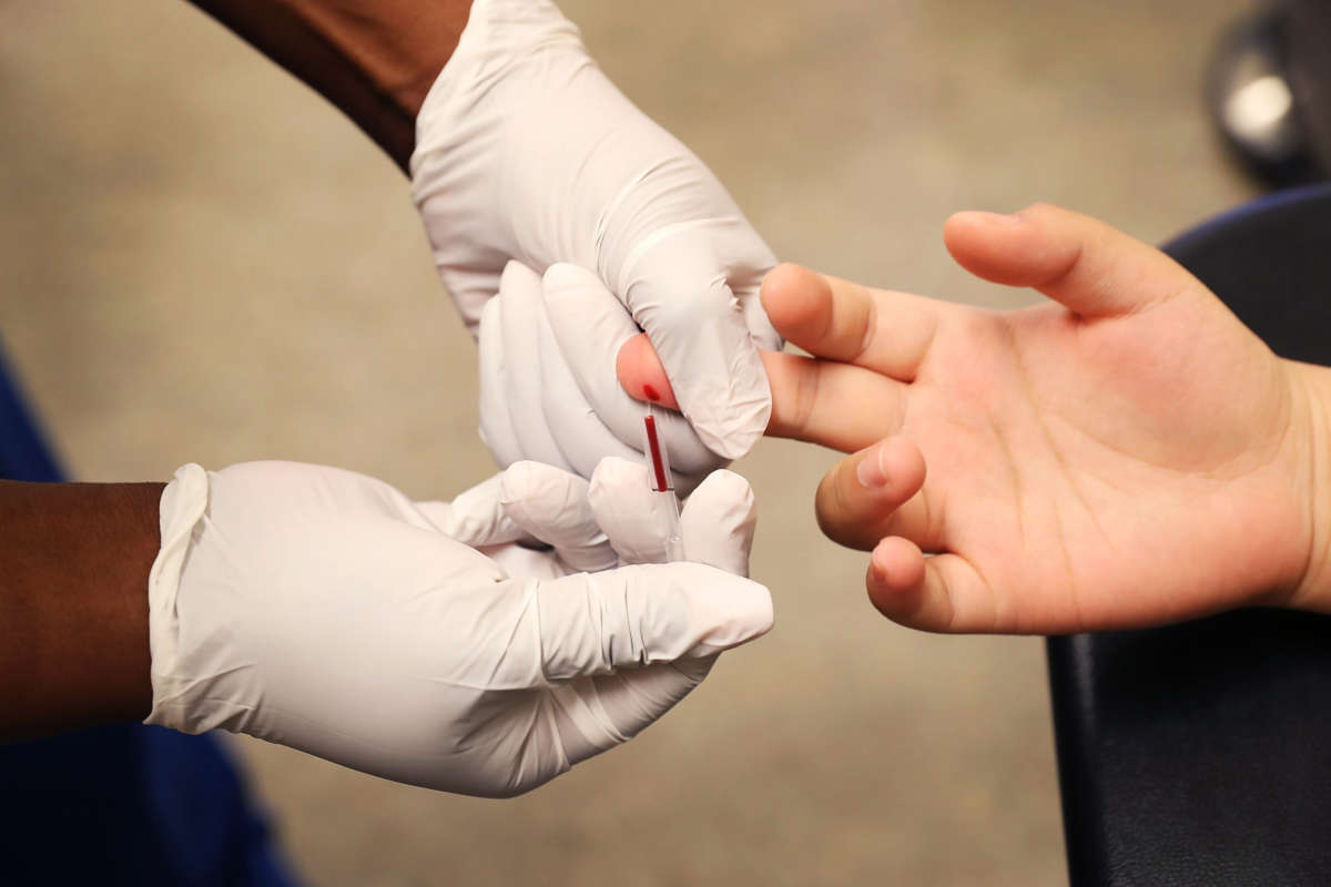 A person gets their hand pricked during a HIV test