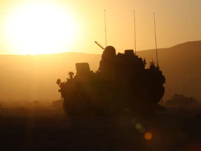 A tank is backlit by the setting sun