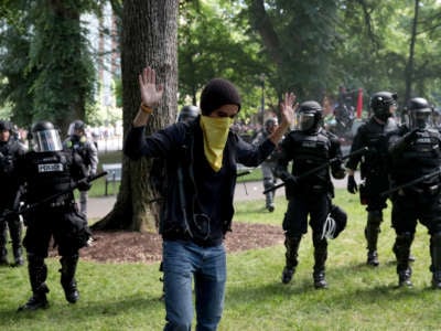 A person raises their hands as police clash with demonstrators as they move to clear the area during a protest on June 4, 2017, in Portland, Oregon.