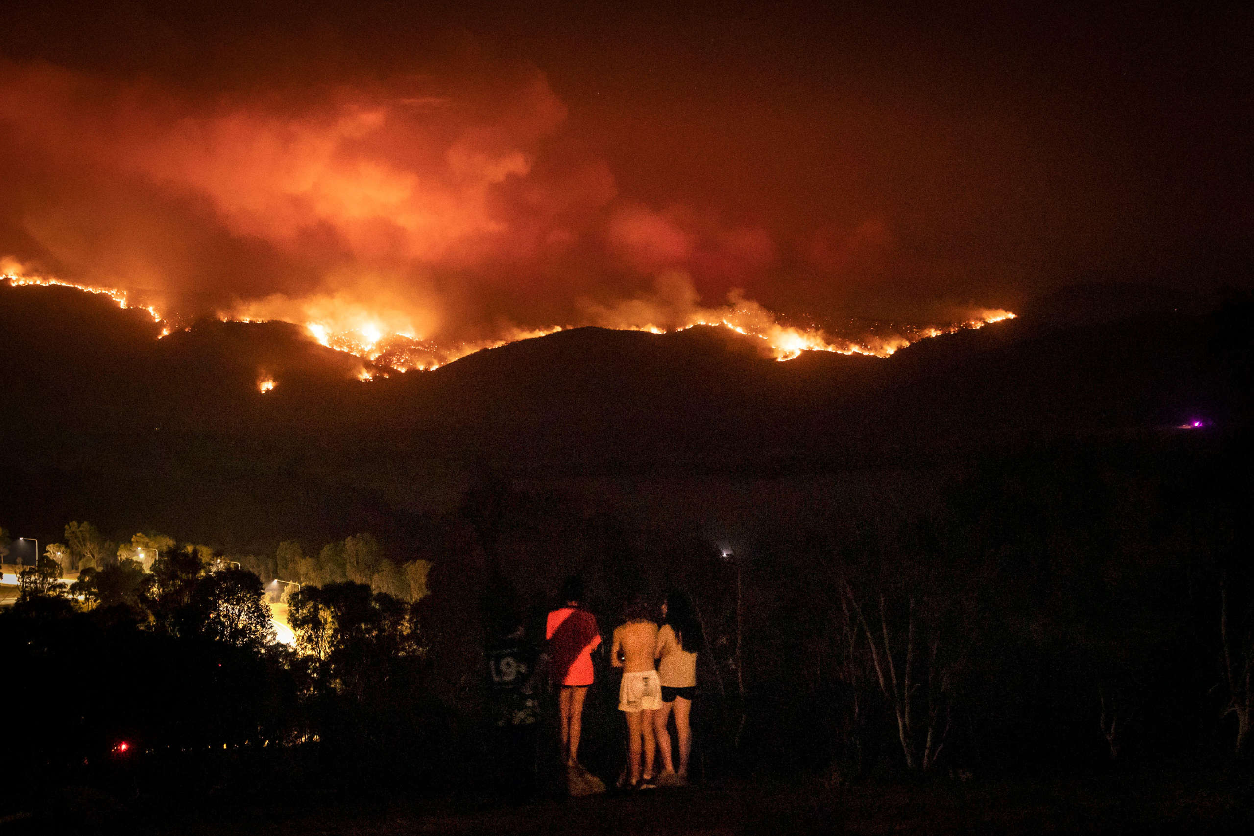 Local residents watch as fire burns to the suburban fringe of the city of Canberra, Australia, on January 31, 2020.