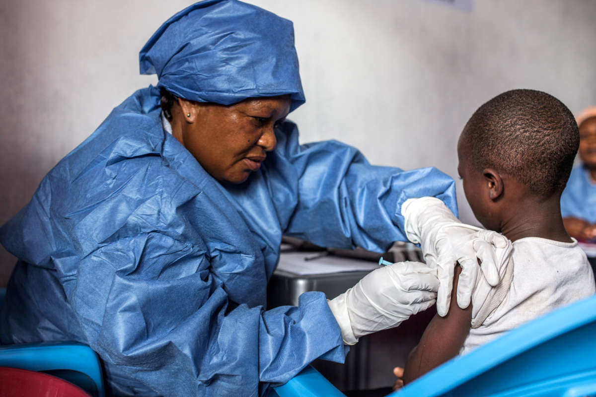 A woman administers a vaccine to a child