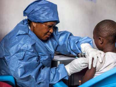 A woman administers a vaccine to a child