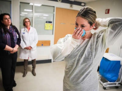 Kaylen Smith demonstrates how to don the protective gear that must be worn when dealing with patients with an infectious disease as Massachusetts General Hospital in Boston prepares for a possible surge in coronavirus patients on February 27, 2020.