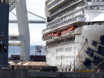 Tents are set up at the dock a large cruise ship is docked at