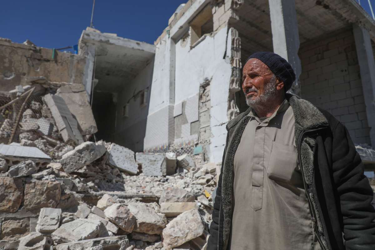 A man stands by the ruins of what was once his home