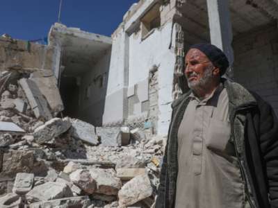 A man stands by the ruins of what was once his home