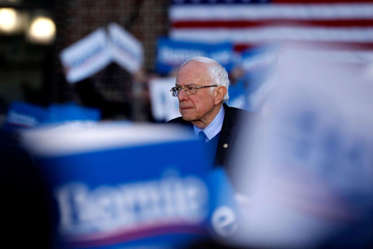 Bernie Sanders stands among the signs his followers are waving at a rally