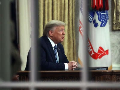 President Trump is seen through a window in the Oval Office as he addresses the nation on the response to the COVID-19 coronavirus on March 11, 2020, in Washington, D.C.