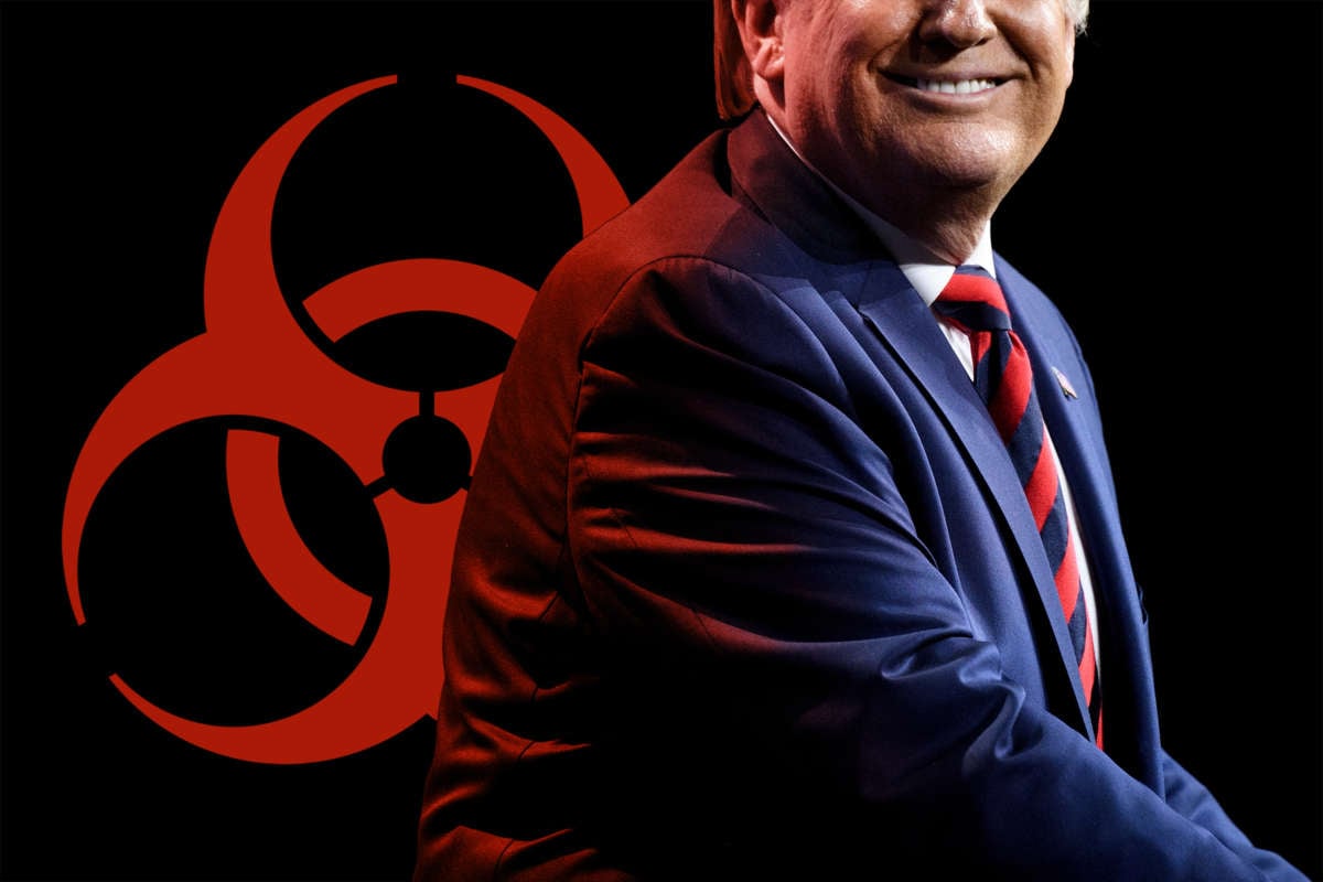Donald trump sits, smiling, in front of the biohazard symbol