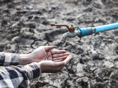 Cupped hands hover expectantly beneath a shut-off faucet