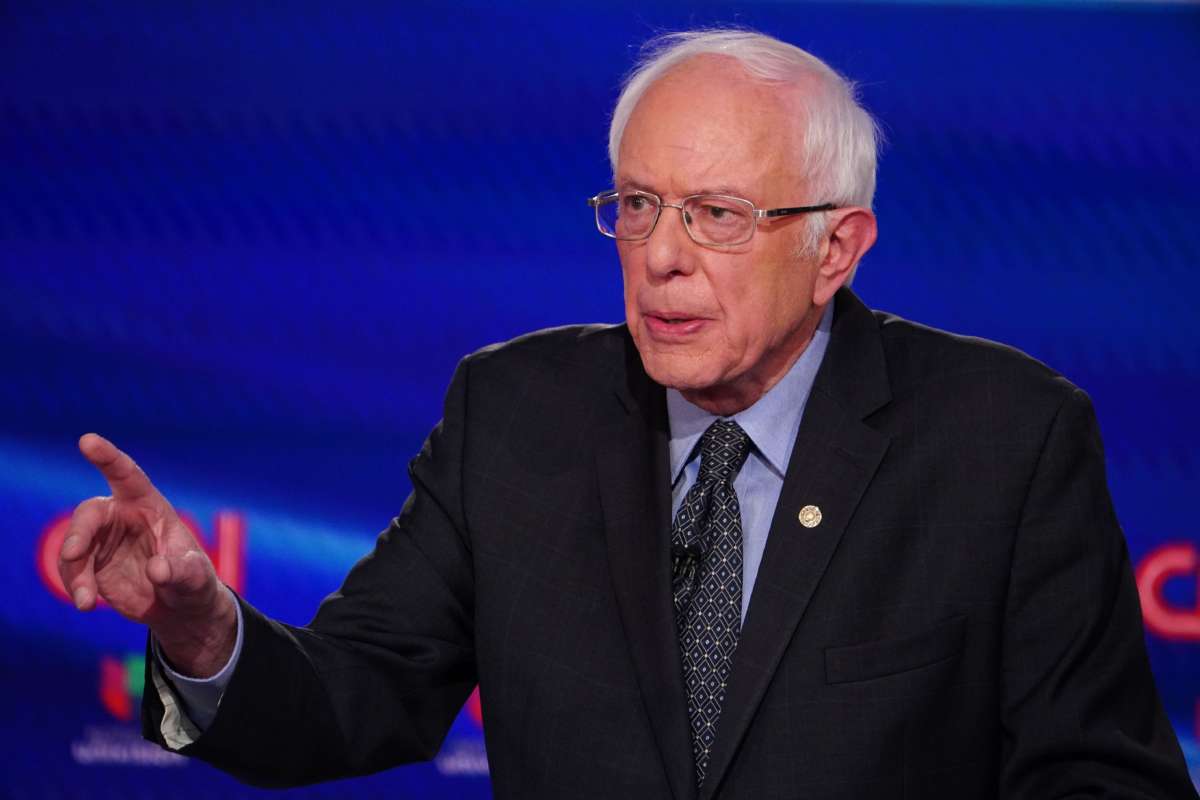 Bernie Sanders speaks in front of a blue screen bearing CNN's logo