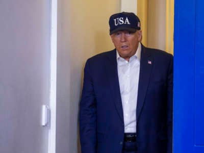 Donald Trump wears a hat reading USA
