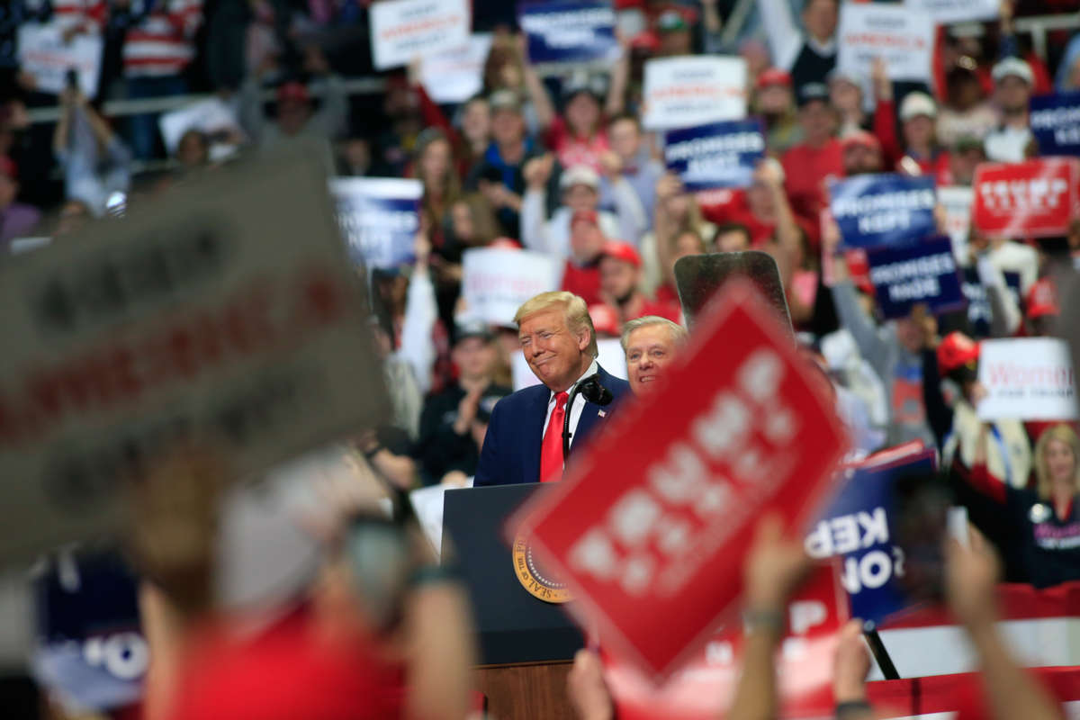 Donald trump grins while standing at a podium during a rally