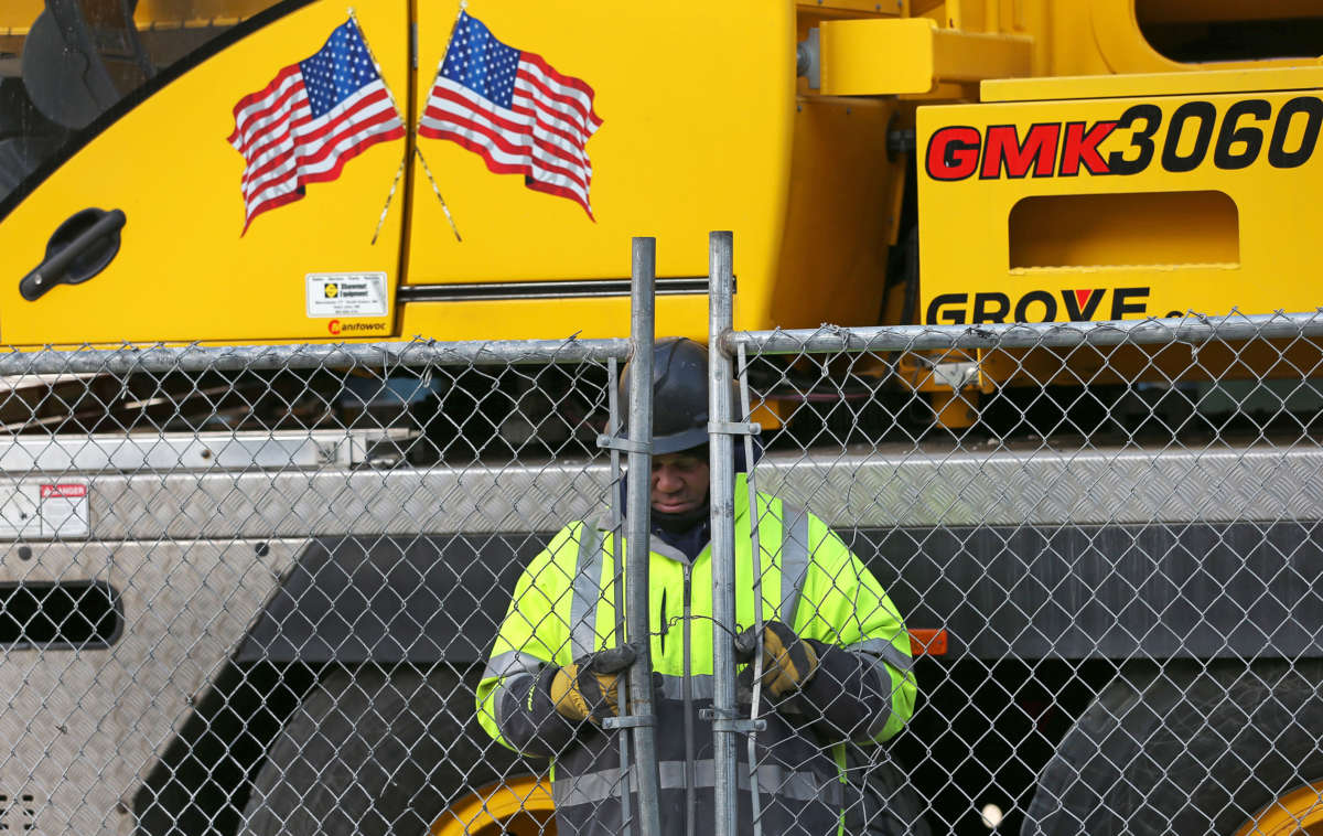 A construction worker locks up the gate at the end of the day in Boston's Seaport on March 16, 2020. Boston ordered a halt to major businesses and city construction projects.