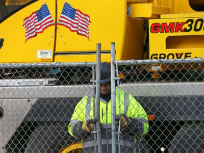 A construction worker locks up the gate at the end of the day in Boston's Seaport on March 16, 2020. Boston ordered a halt to major businesses and city construction projects.