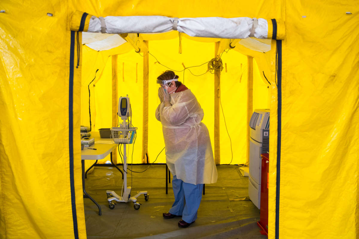 Nurse practitioner Amy Israelian puts on protective gear in a tent in the parking lot of the Newton-Wellesley Hospital before testing a possible coronavirus patient in Newton, Massachusetts, on March 16, 2020.