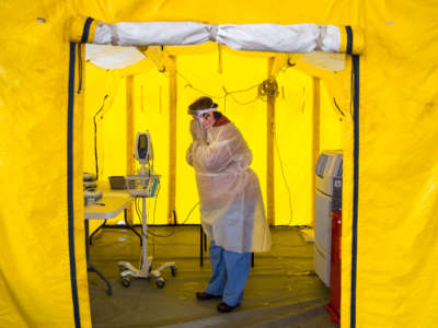 Nurse practitioner Amy Israelian puts on protective gear in a tent in the parking lot of the Newton-Wellesley Hospital before testing a possible coronavirus patient in Newton, Massachusetts, on March 16, 2020.