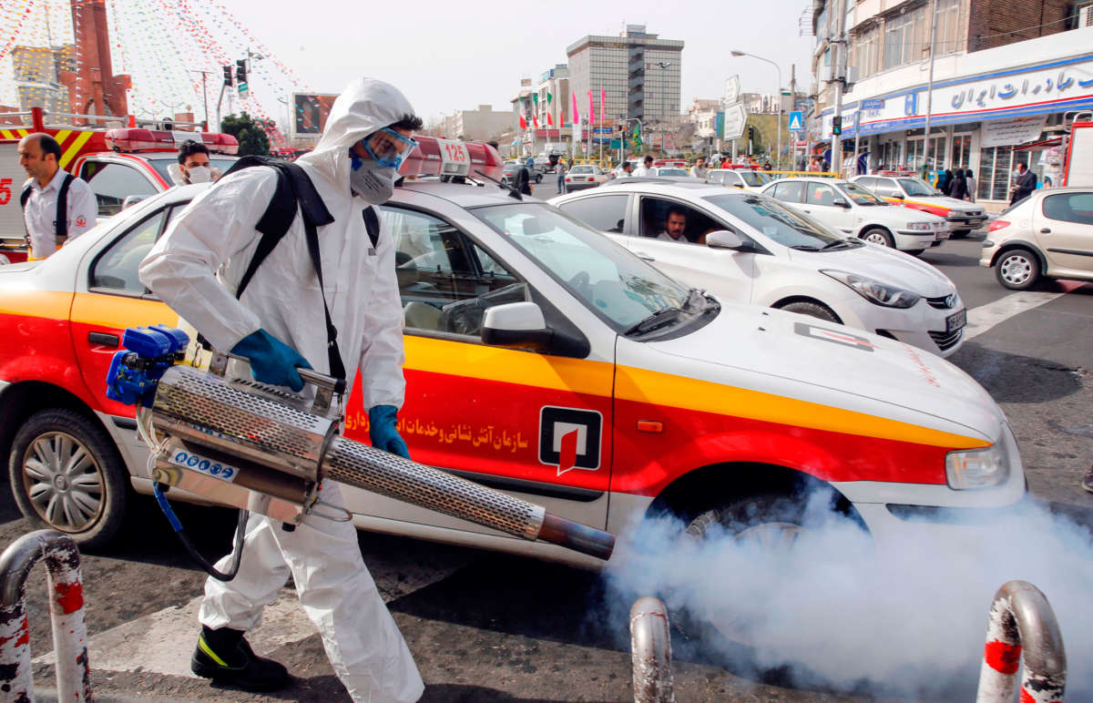 An Iranian firefighter disinfects a street in Tehran, Iran, in a bid to halt the wild spread of coronavirus on March 13, 2020.