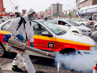 An Iranian firefighter disinfects a street in Tehran, Iran, in a bid to halt the wild spread of coronavirus on March 13, 2020.