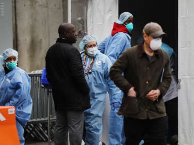 Medical workers and other officials gather outside of the Brooklyn Hospital Center where testing for the coronavirus has started on March 19, 2020, in the Brooklyn borough of New York City.