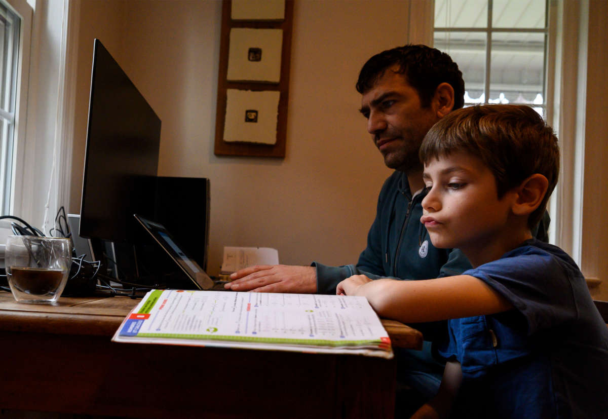 Joachim, 8, whose school was closed following the Coronavirus outbreak, does school exercises at home with his dad Pierre-Yves in Washington on March 20, 2020.