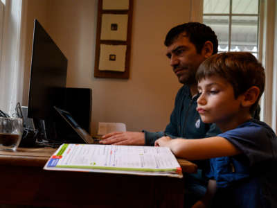 Joachim, 8, whose school was closed following the Coronavirus outbreak, does school exercises at home with his dad Pierre-Yves in Washington on March 20, 2020.