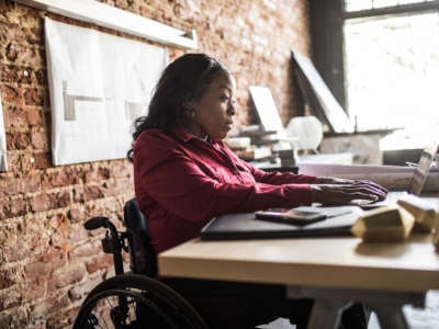 A woman in a wheelchair works on a computer