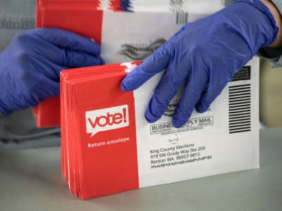An election worker wearing protective gloves sorts through mailed-in ballots in the King County Elections ballot processing center on March 9, 2020, in Renton, Washington.