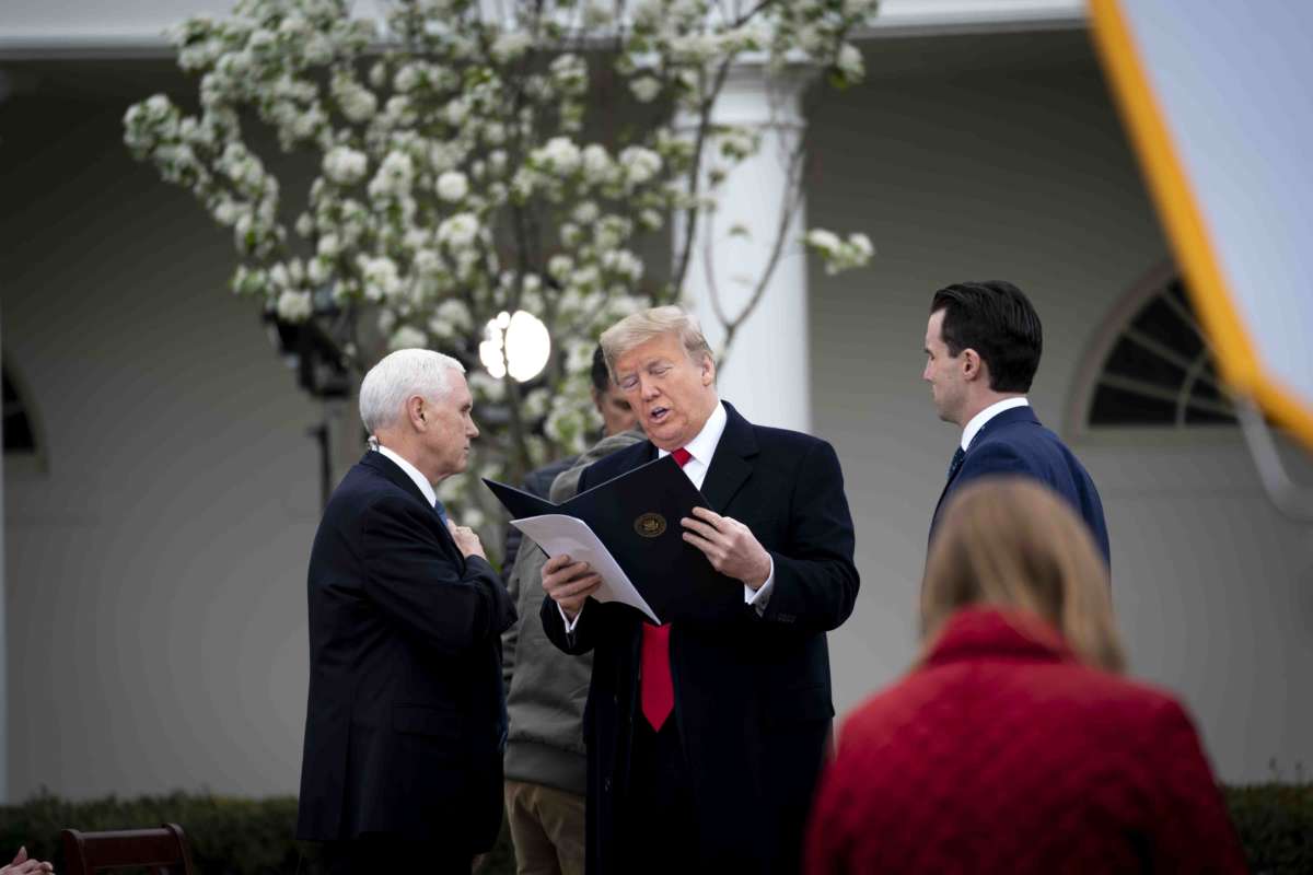 Donald Trump looks at a bill alongside mike pence