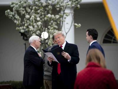 Donald Trump looks at a bill alongside mike pence