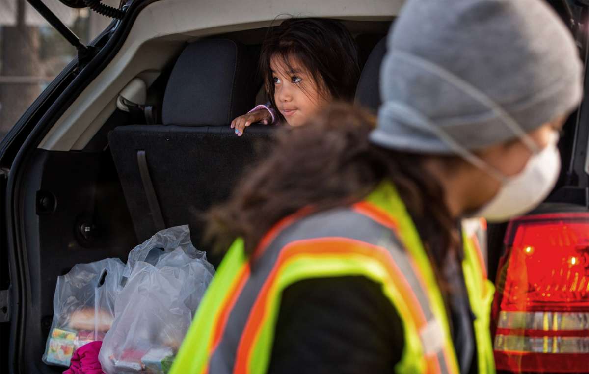 A child looks out the back of a vehicle after receiving meals from the LAUSD "grab and go" center at Van Nuys High School on March 18, 2020.