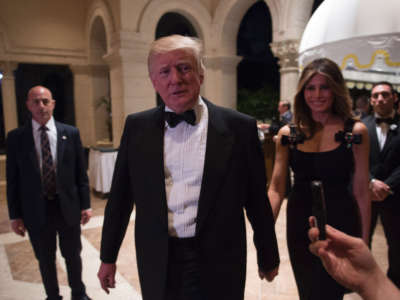Then-President-elect Donald Trump answers questions from reporters accompanied by his wife Melania for a New Year's Eve party December 31, 2016, at Mar-a-Lago in Palm Beach, Florida.