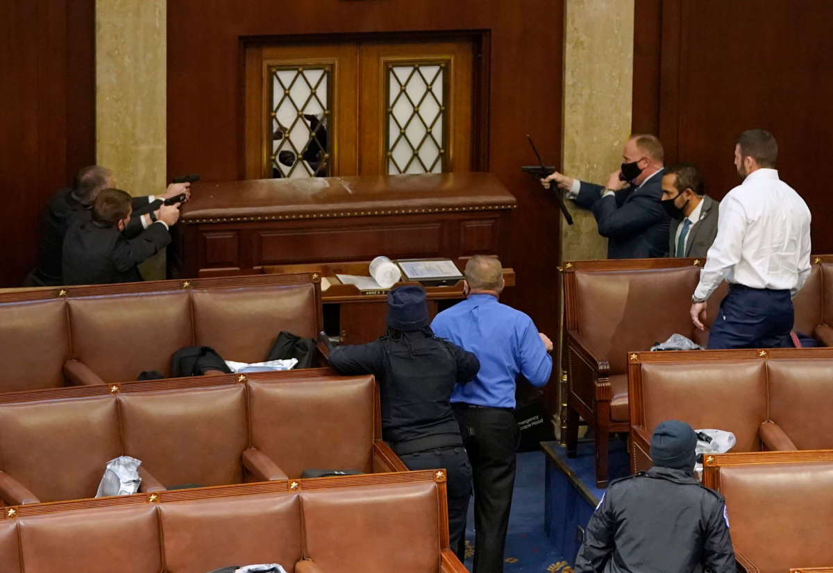 U.S. Capitol police officers point their guns at a door that was vandalized in the House Chamber during a joint session of Congress on January 6, 2021, in Washington, D.C.