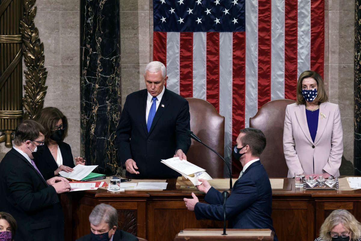 Vice President Mike Pence hands the West Virginia certification to staff as Speaker of the House Nancy Pelosi listens during a joint session of Congress after working through the night, at the Capitol on January 7, 2021, in Washington, D.C.