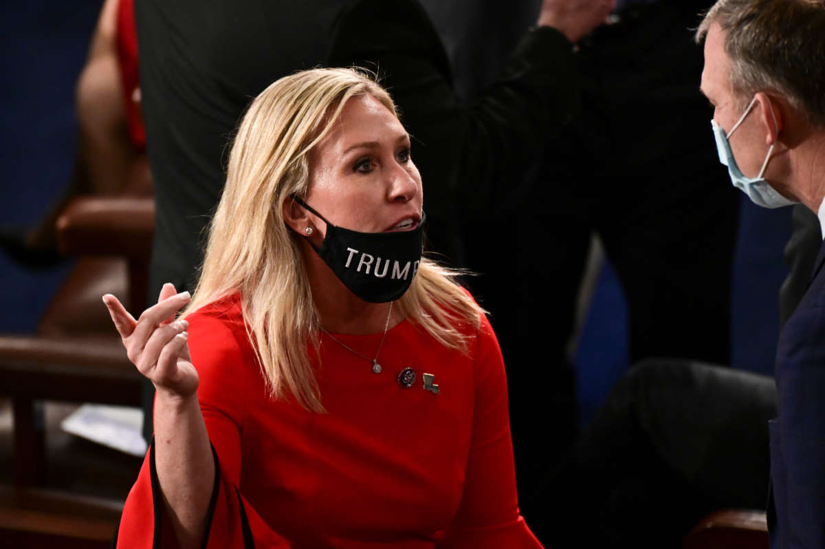 Rep. Marjorie Taylor Greene, with her "Trump Won" face mask pulled down, speaks to a colleague on the new year's opening session on January 3, 2021, in Washington, D.C.