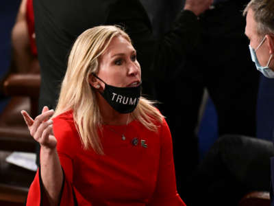 Rep. Marjorie Taylor Greene, with her "Trump Won" face mask pulled down, speaks to a colleague on the new year's opening session on January 3, 2021, in Washington, D.C.