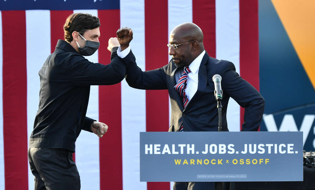 Georgia Democratic Senate candidates Jon Ossoff and Raphael Warnock greet each other onstage during a "Vote GA Blue" concert at New Birth Church on December 28, 2020, at New Birth Church in Stonecrest, Georgia.