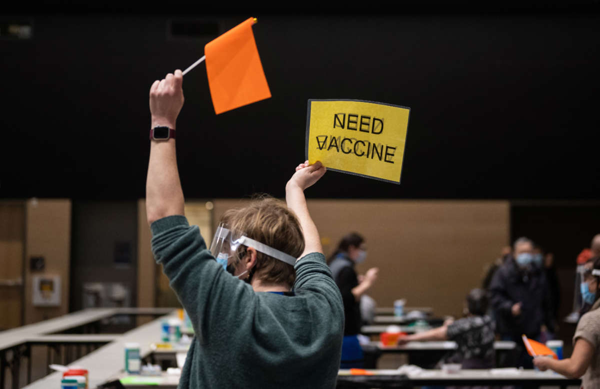 A Virgina Mason advanced registered nurse practitioner holds up a sign and a flag asking for another patient to dose with the Pfizer Covid-19 vaccine as well as a refill during a partnership with the hospital network and Amazon at the Amazon Meeting Center in downtown Seattle, Washington, on January 24, 2021.