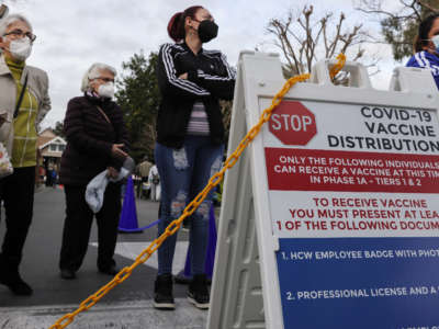 People wait outside a COVID-19 vaccine distribution center at the Kedren Community Health Center on January 28, 2021, in Los Angeles, California.