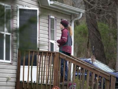 Aperson in a maroon shirt speaks to someone through their open door