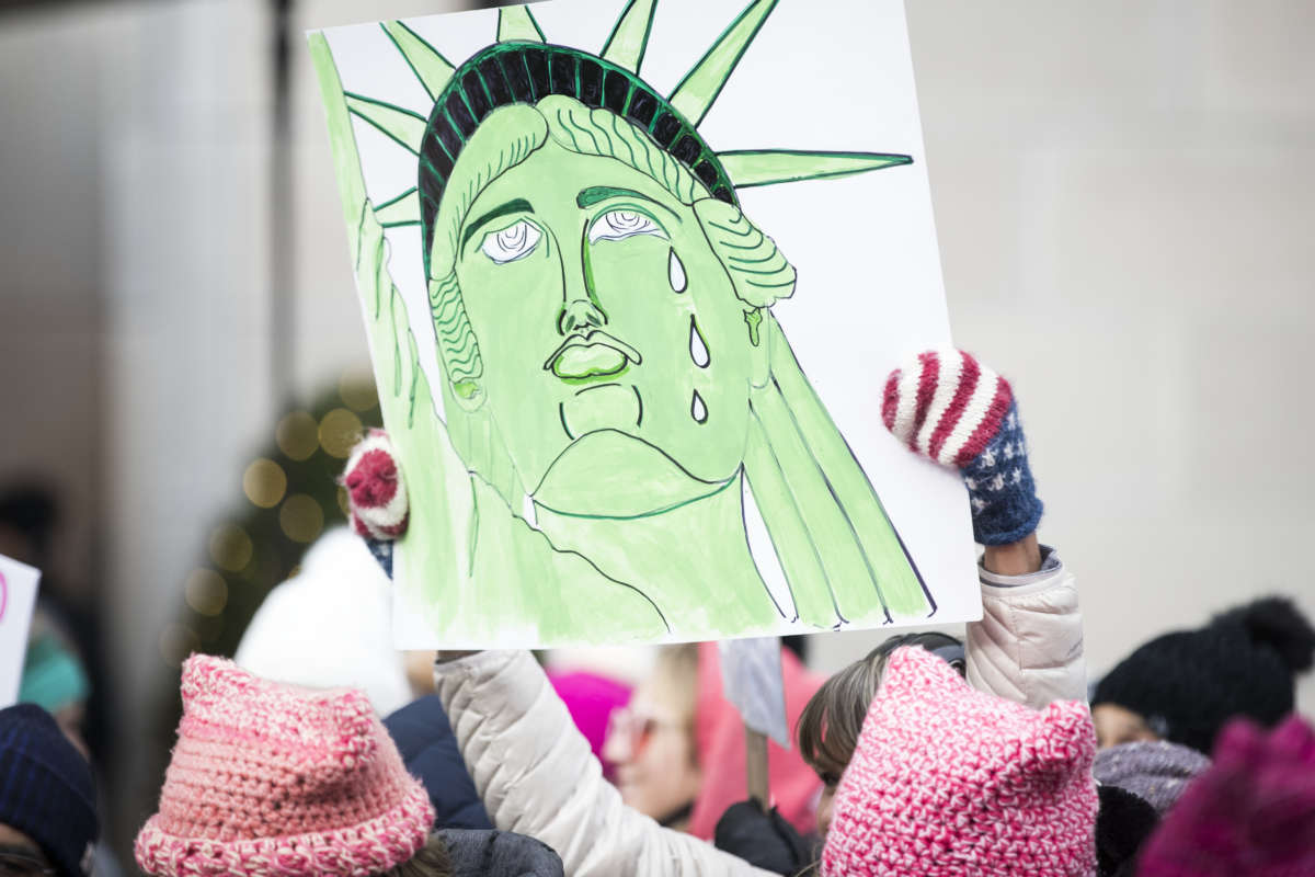 A marcher holds a sign that shows the Statue of Liberty with tears running down her face during the Women's March in the borough of Manhattan in NY on January 18, 2020.