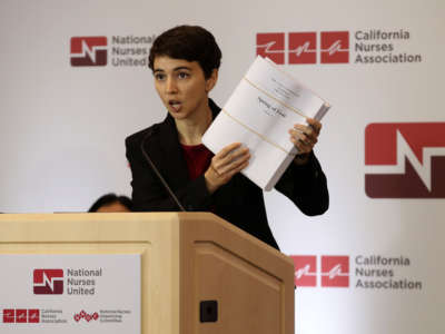 Jane Thomason, an industrial hygienist for National Nurses United, holds up a report about the SARS virus during a news conference with health care workers at the union's offices on March 5, 2020, in Oakland, California. The union held a news conference to express concerns that the Centers for Disease Control and Prevention is not doing enough to help protect and test health care workers who are exposed to patients with the COVID-19 virus.